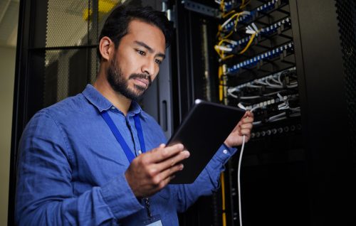 Server room, tablet and engineer with connection cable for maintenance or software update at night. Cybersecurity, it programmer and coder man with technology for database networking in data center