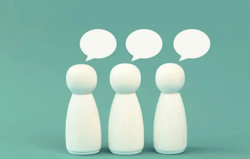 Three white playing pieces used to depict three people on a teal green background.They have speech bubbles above their head to suggest they are getting a second opinion on your Business IT.