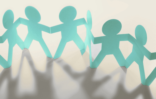 Paper cut-out figures holding hands in a row, symbolising teamwork and collaboration.